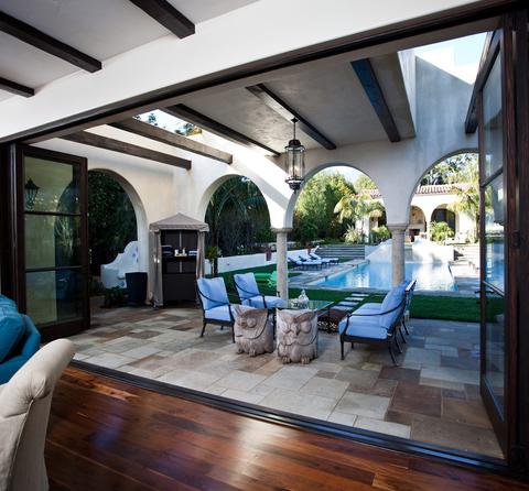 Huge bifold doors open to a patio and pool in a Mediterranean style home.
