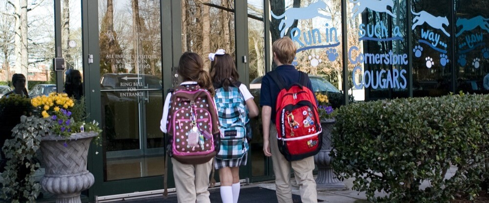 students walking into school with backpacks 
