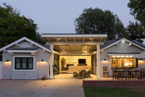 A craftsman style home with bifold doors and windows open in the evening time.