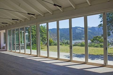 Huge wall of bifold doors overlooking luscious greenery and a bay in northern California.
